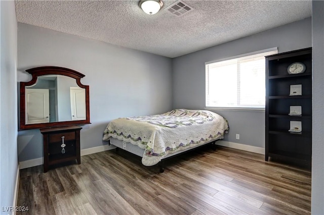 bedroom featuring wood-type flooring and a textured ceiling