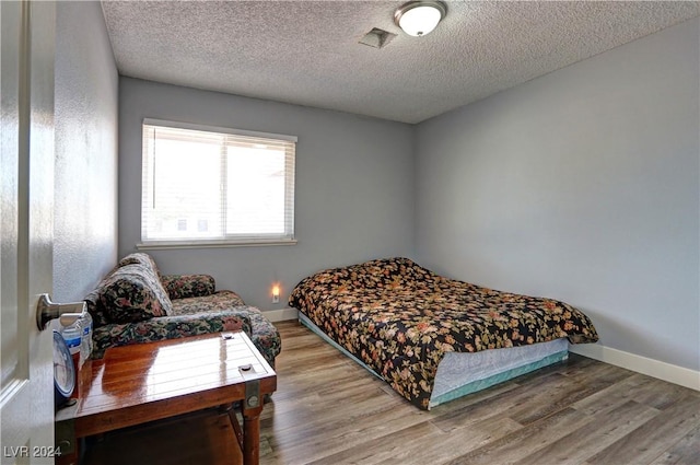 bedroom with hardwood / wood-style flooring and a textured ceiling