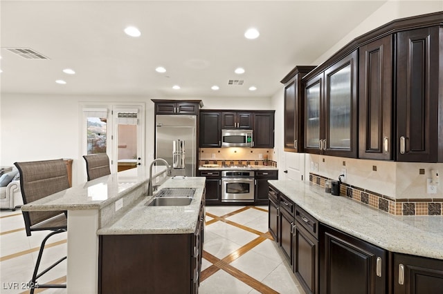 kitchen featuring dark brown cabinetry, sink, stainless steel appliances, a breakfast bar area, and decorative backsplash