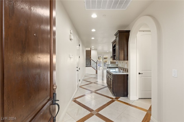 corridor with visible vents, baseboards, arched walkways, stairway, and recessed lighting