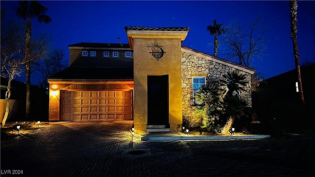 view of front facade featuring a garage, stone siding, and decorative driveway