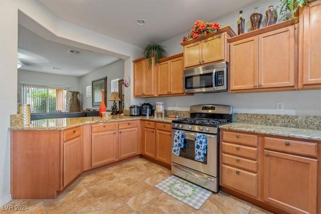 kitchen featuring kitchen peninsula, stainless steel appliances, and light stone countertops