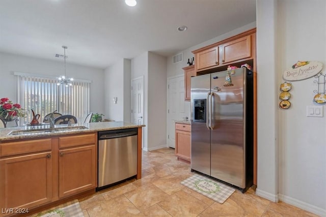 kitchen featuring light stone countertops, stainless steel appliances, sink, a notable chandelier, and hanging light fixtures