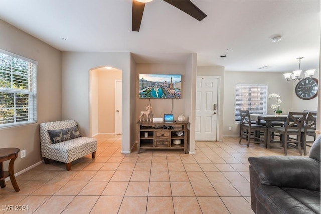 living room with ceiling fan with notable chandelier and light tile patterned floors