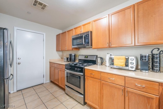 kitchen with light tile patterned floors and stainless steel appliances