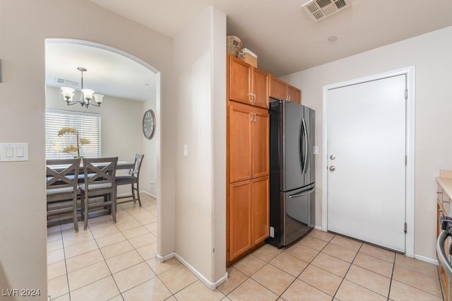 kitchen featuring light tile patterned flooring, stainless steel fridge, an inviting chandelier, and pendant lighting