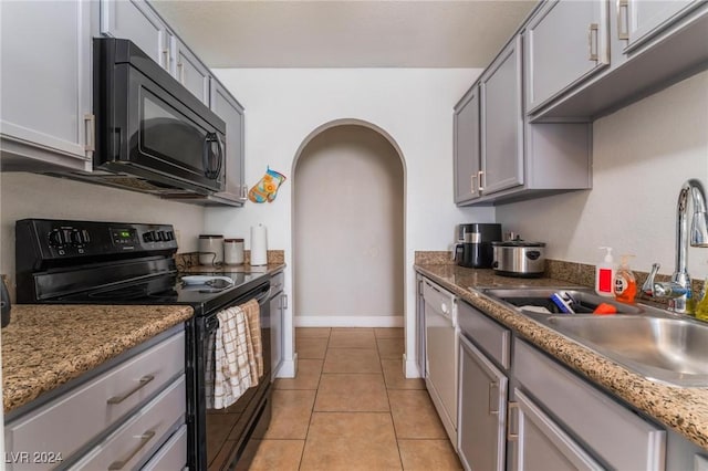 kitchen with light stone counters, sink, black appliances, light tile patterned floors, and gray cabinets