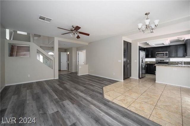 unfurnished living room featuring ceiling fan with notable chandelier and dark hardwood / wood-style flooring