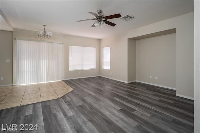 spare room featuring ceiling fan with notable chandelier and dark wood-type flooring