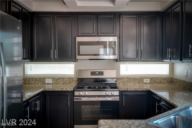 kitchen featuring light stone countertops, sink, dark brown cabinets, and appliances with stainless steel finishes