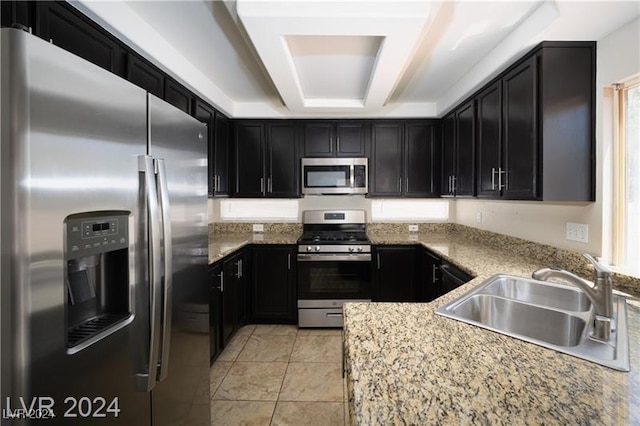 10142 Rice Paper St, Las Vegas, NV 89183 - kitchen with stainless steel appliances, dark cabinets, light stone countertops, and a raised ceiling