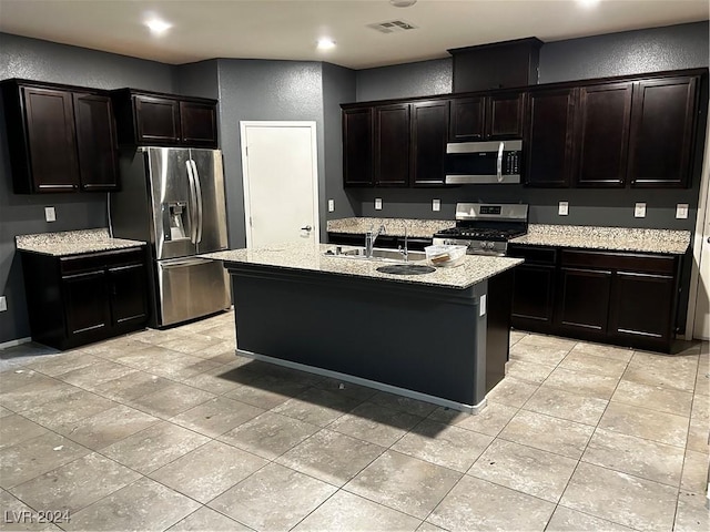 kitchen featuring dark brown cabinetry, a center island with sink, stainless steel appliances, and sink