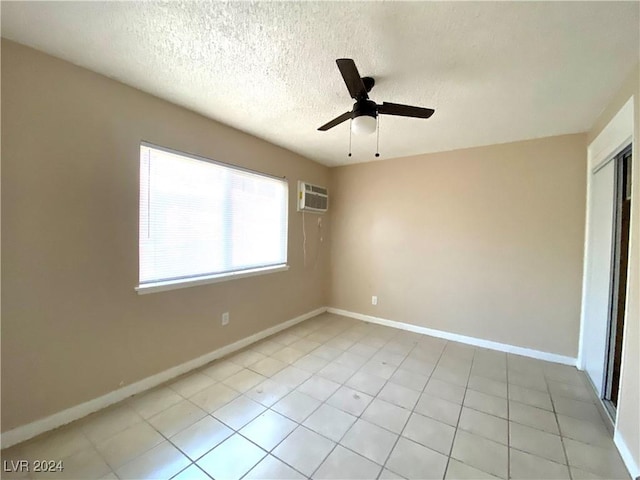 tiled empty room with a textured ceiling, a wall mounted AC, and ceiling fan