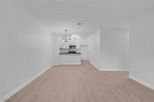 unfurnished living room featuring light hardwood / wood-style flooring and an inviting chandelier