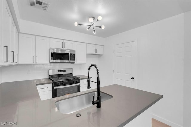 kitchen with sink, stainless steel appliances, kitchen peninsula, decorative backsplash, and white cabinets