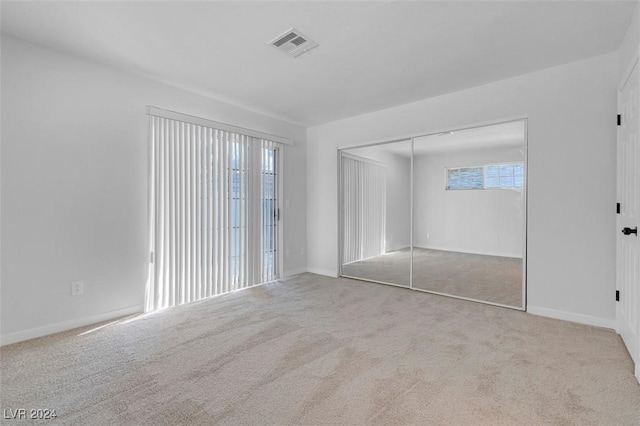 unfurnished bedroom with a closet, light carpet, and multiple windows