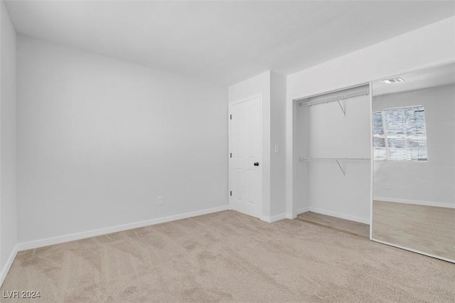 unfurnished bedroom with light carpet and a closet