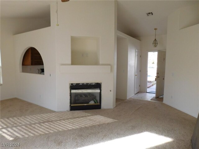 unfurnished living room with light carpet and high vaulted ceiling