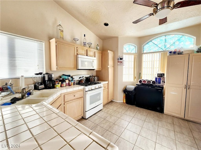 kitchen with tile countertops, a textured ceiling, lofted ceiling, white appliances, and light tile patterned floors