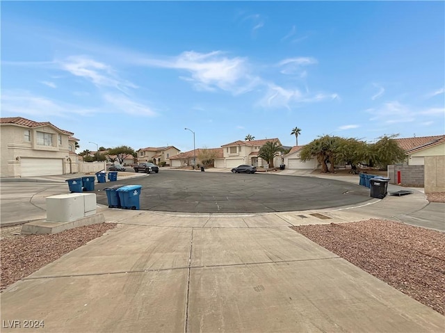 view of road featuring concrete driveway, street lighting, and a residential view