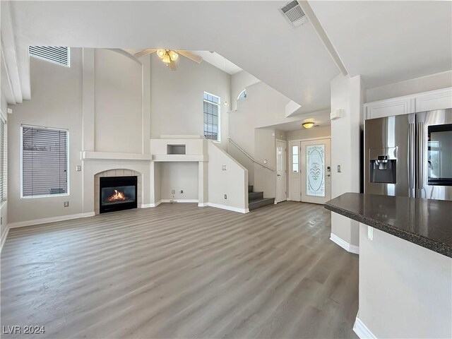 unfurnished living room with high vaulted ceiling, plenty of natural light, and a fireplace