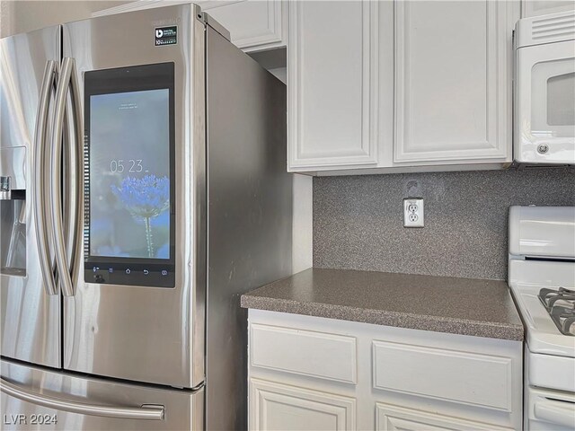 kitchen featuring dark countertops, white appliances, tasteful backsplash, and white cabinets