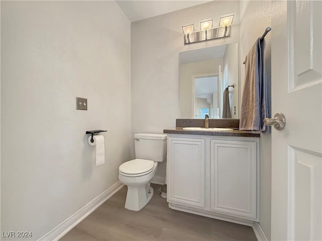 bathroom with toilet, baseboards, wood finished floors, and vanity