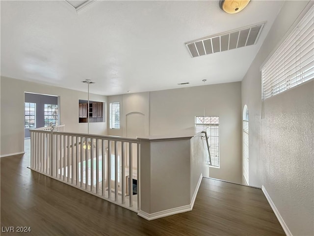 hall featuring visible vents, baseboards, and wood finished floors