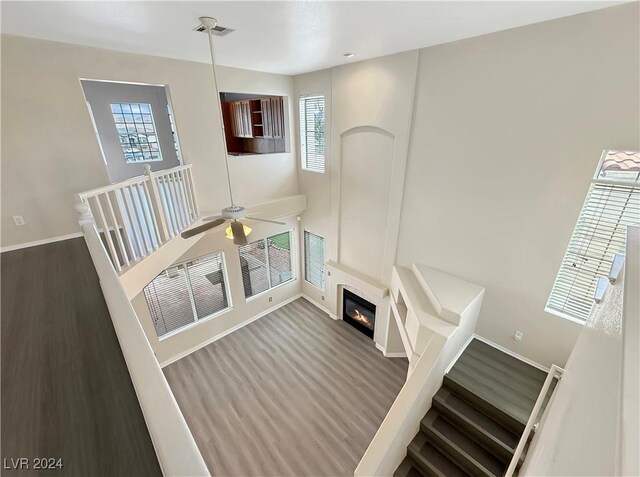 living area featuring wood finished floors, visible vents, baseboards, stairway, and a glass covered fireplace