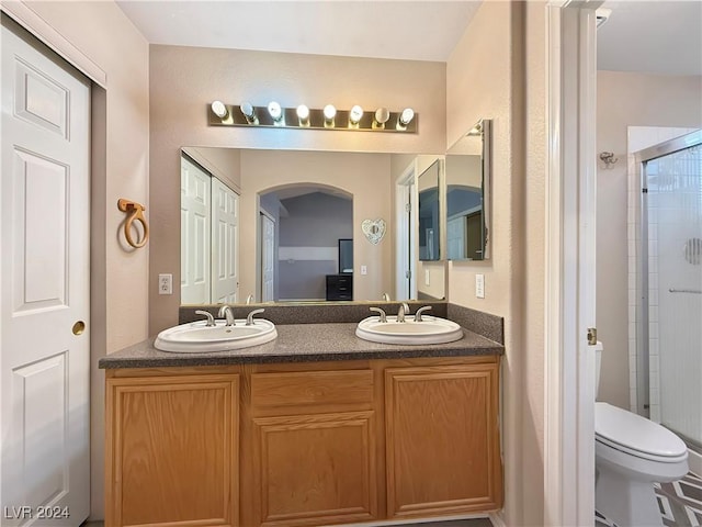 bathroom with a sink, a shower stall, toilet, and double vanity