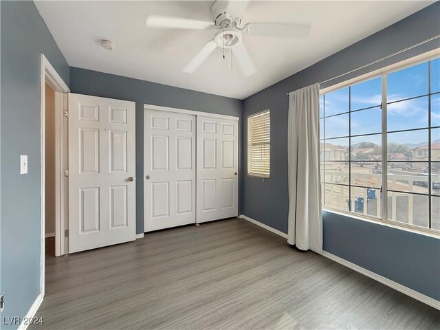 unfurnished bedroom with a closet, wood finished floors, a ceiling fan, and baseboards