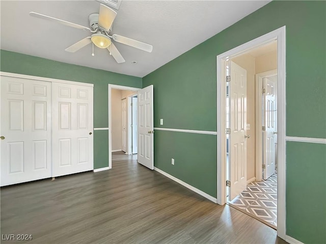 unfurnished bedroom with ceiling fan, a closet, baseboards, and wood finished floors