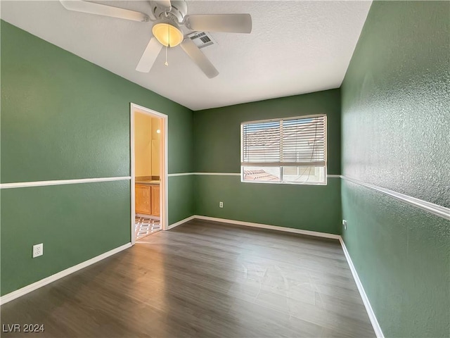 unfurnished room featuring a textured wall, wood finished floors, and baseboards