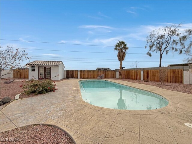 view of swimming pool with a fenced backyard, a patio, a fenced in pool, and an outdoor structure