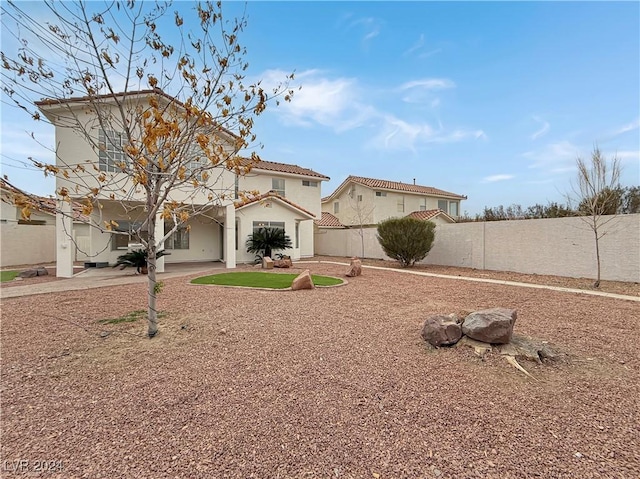 view of front of house featuring a tile roof, a patio area, fence, and stucco siding