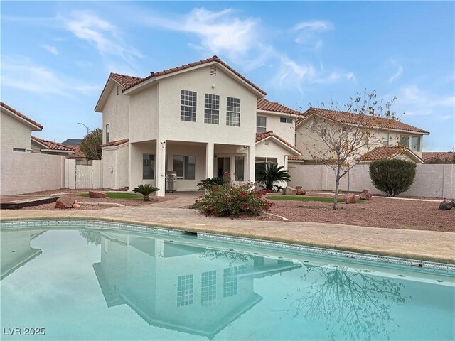 rear view of house with a fenced in pool, a fenced backyard, a patio, and stucco siding