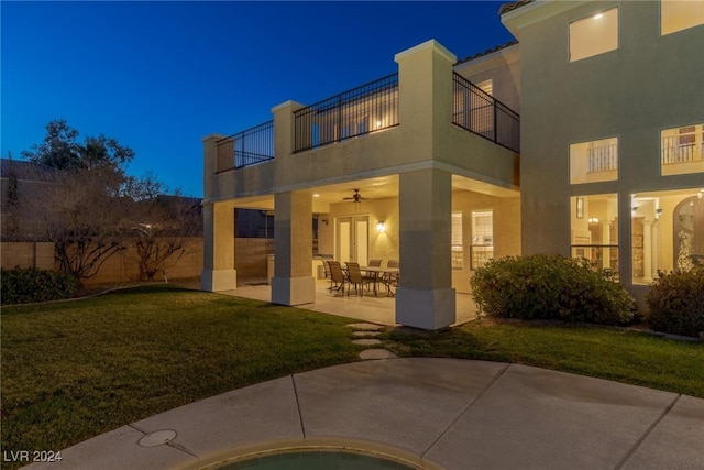 back of property featuring a balcony, a patio area, and a lawn