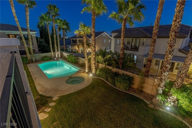 pool at night featuring an in ground hot tub and a patio