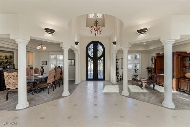 tiled entryway with a healthy amount of sunlight, a towering ceiling, french doors, and a notable chandelier