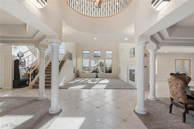 entryway featuring a high ceiling, plenty of natural light, and a tiled fireplace