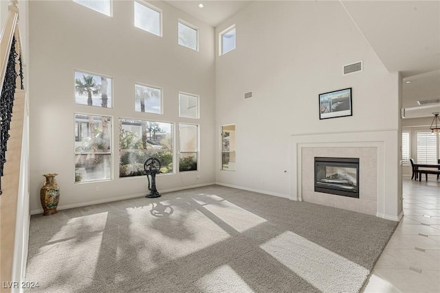 unfurnished living room featuring a towering ceiling, light carpet, and a tile fireplace