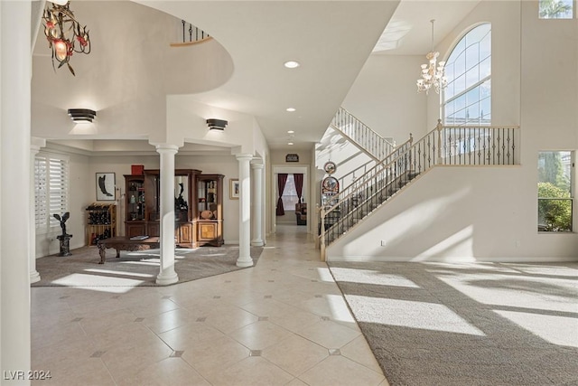 carpeted entryway with decorative columns, a high ceiling, and a notable chandelier