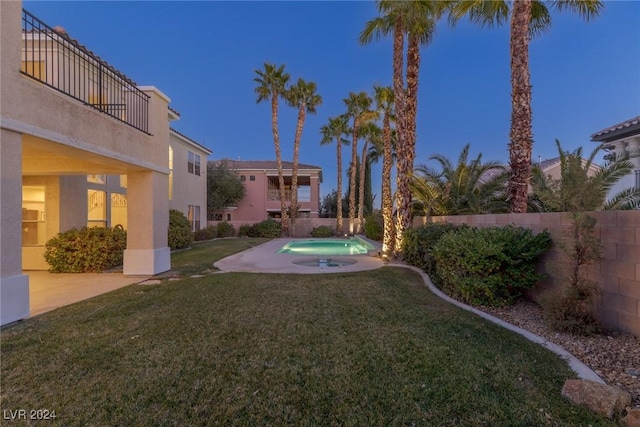 yard at dusk with a fenced in pool, a patio area, and a balcony