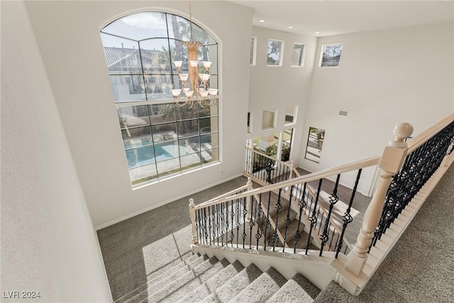 stairway with a chandelier and carpet floors