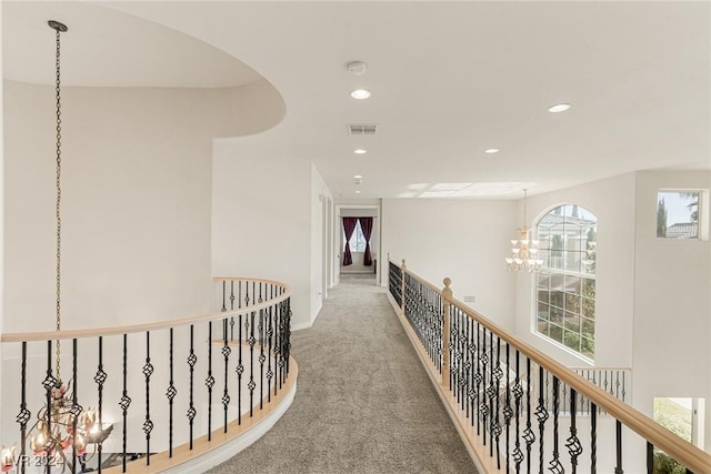 hallway with carpet and a chandelier