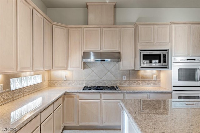 kitchen with tasteful backsplash, light stone countertops, and appliances with stainless steel finishes