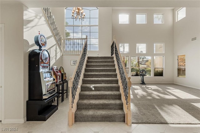 stairway featuring a high ceiling, carpet floors, an inviting chandelier, and a healthy amount of sunlight