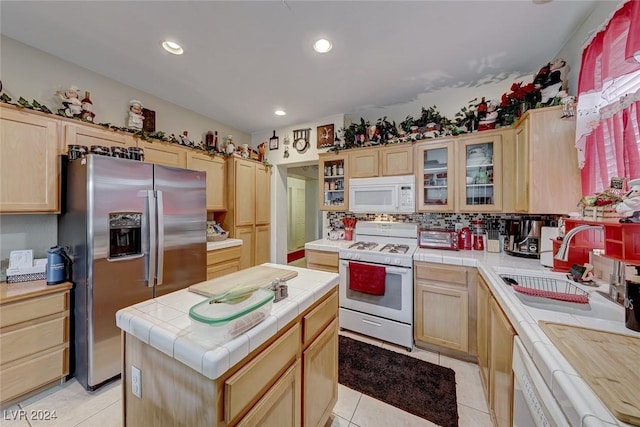 kitchen featuring white appliances, sink, light brown cabinets, tile countertops, and a kitchen island