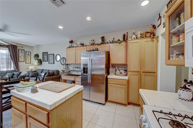 kitchen featuring tile countertops, a kitchen island, stainless steel fridge with ice dispenser, and white stove