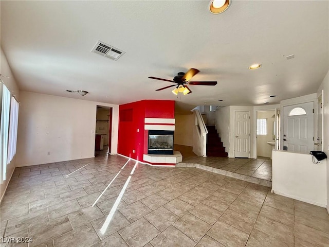 unfurnished living room featuring ceiling fan, a fireplace, and a healthy amount of sunlight